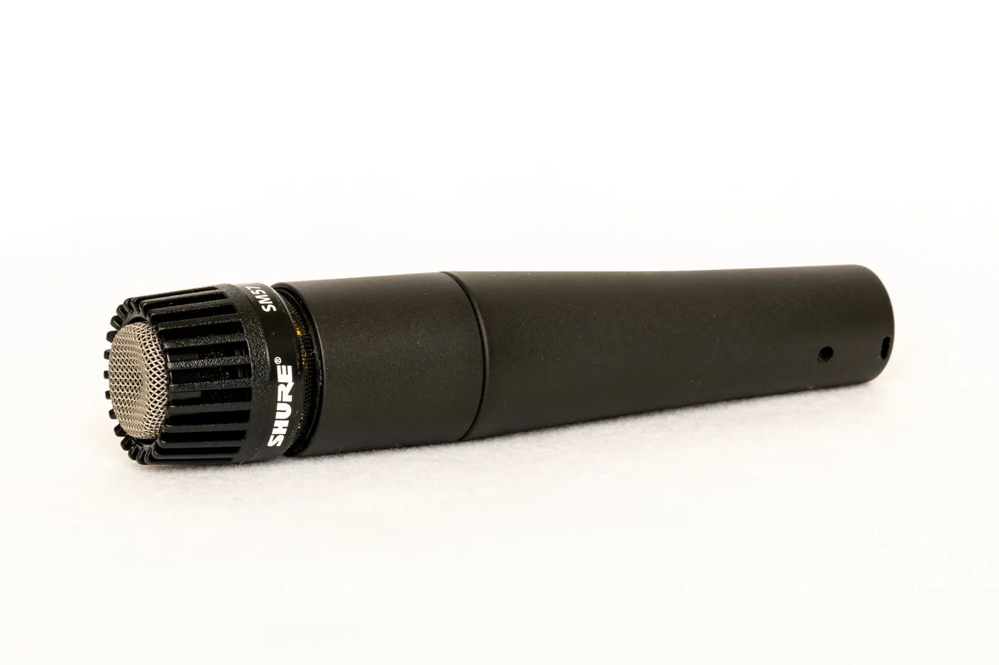 Shure SM57 dynamic microphone lying on a white surface